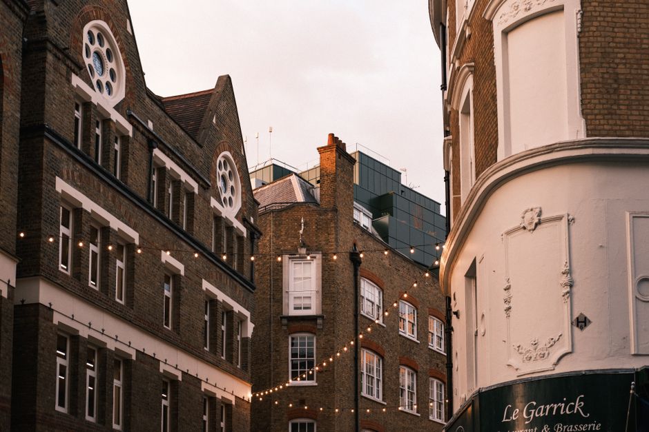 A row of two-storey terraced houses with light blue and dark blue facades, each featuring white-framed sash windows and front doors, one of which is decorated with a festive wreath. Black wrought-iron